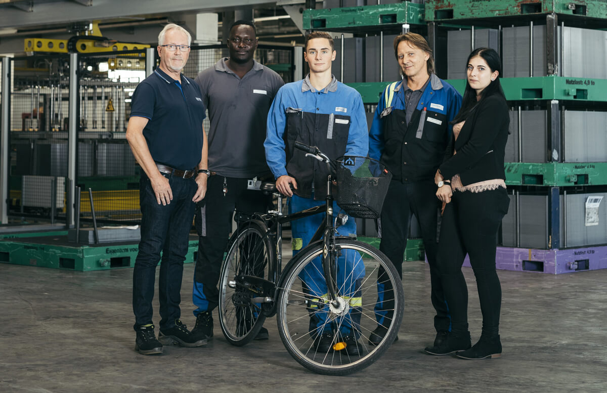 Diverse group of employees posing with a bicycle