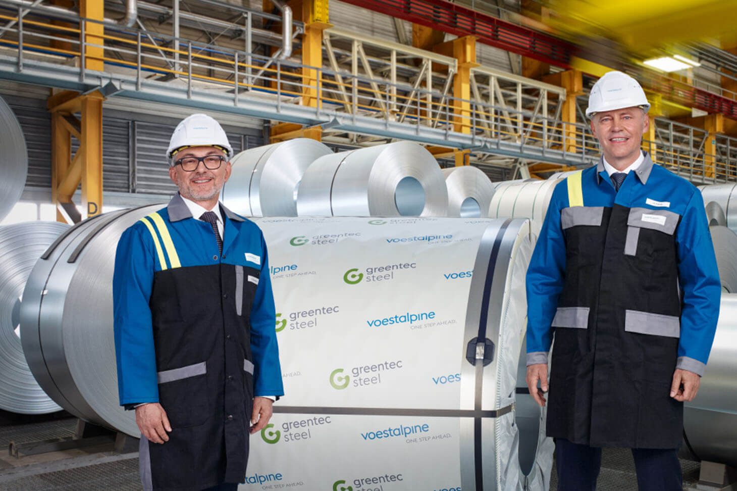 Two employees in front of steel rolls from the delivery