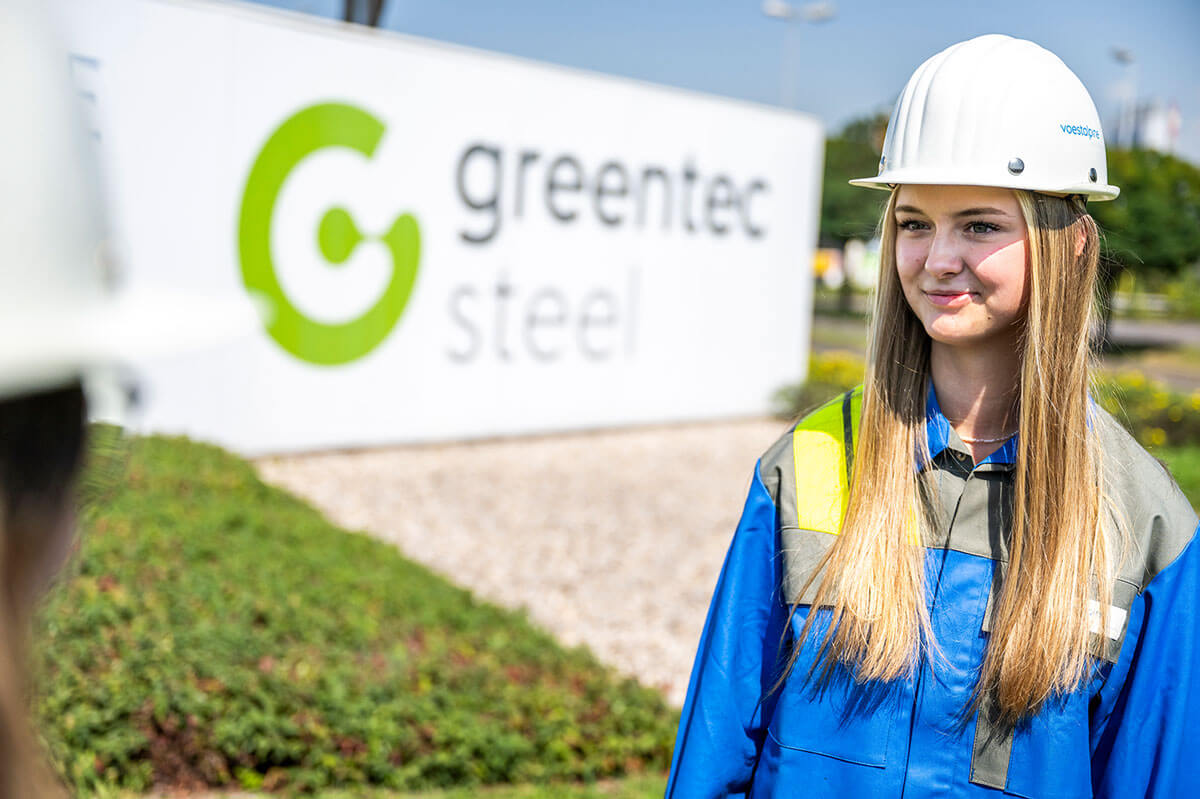 Young Voestalpine employee in front of the greentec sign in Donawitz