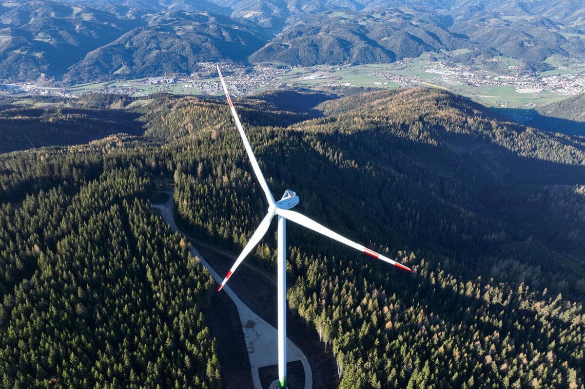 Aerial view of wind turbine in the middle of a wooded hill