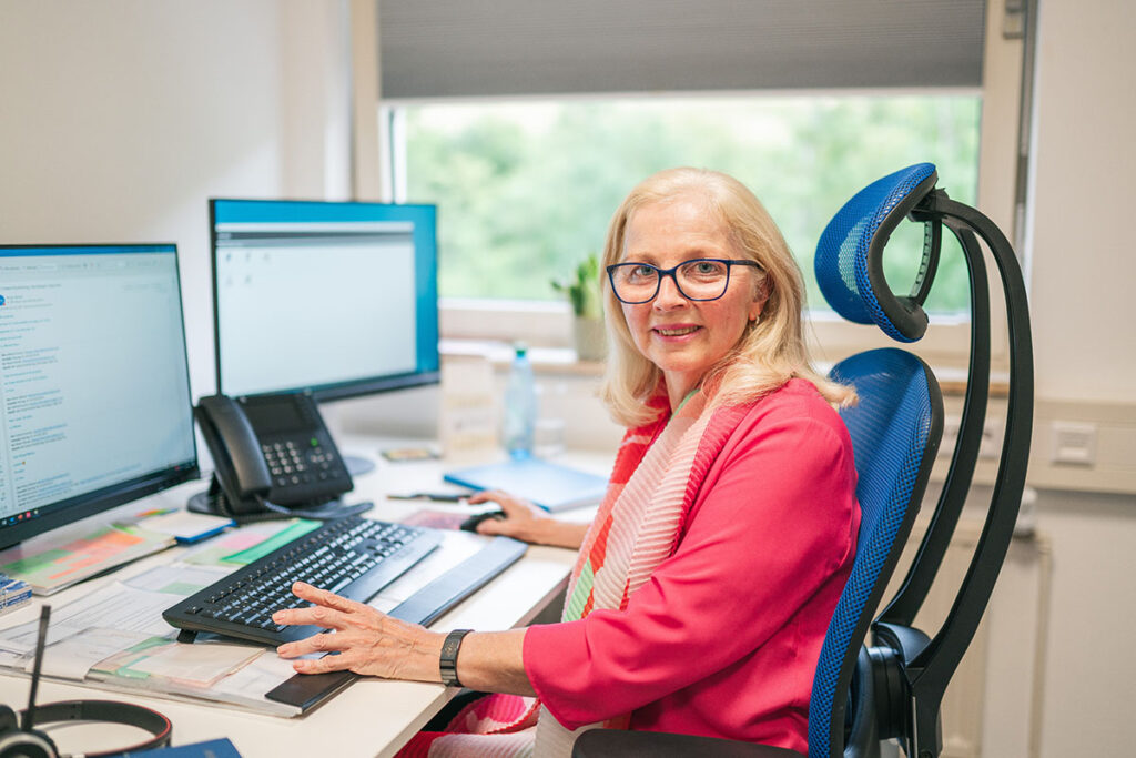 Susanne Gutbrod Portrait an Ihrem Arbeitsplatz mit Standcomputer