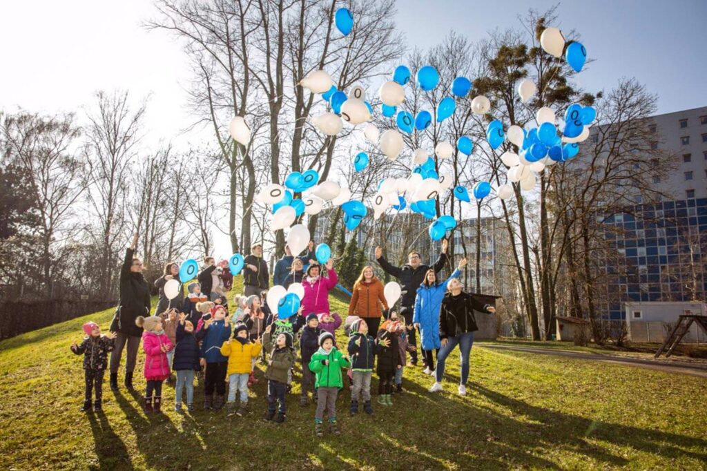 Erwachsene und Kinder lassen blaue und weiße Lufballons fliegen