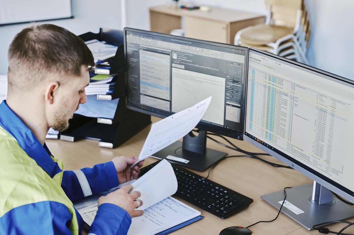 voestalpine employee Thomas working at his desk in front of two screens with a folder
