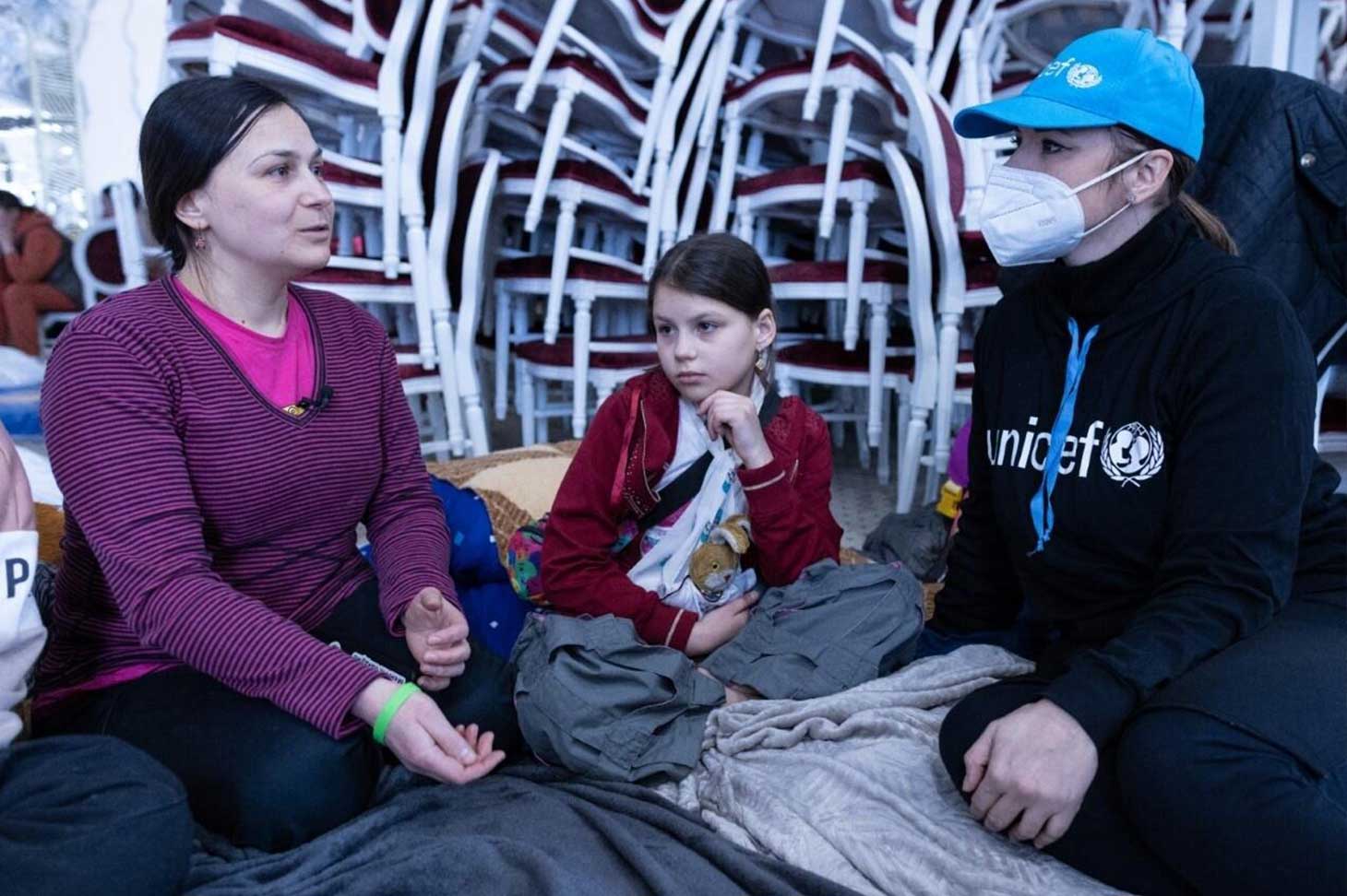 Zwei Frauen und ein Mädchen sitzen am Boden in einem Blue Dot-Familienzentren, das von der voestalpine unterstützt wird