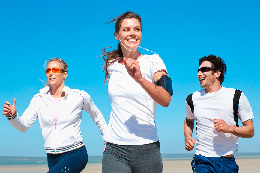 Four runners in a white shirt are running on the beach