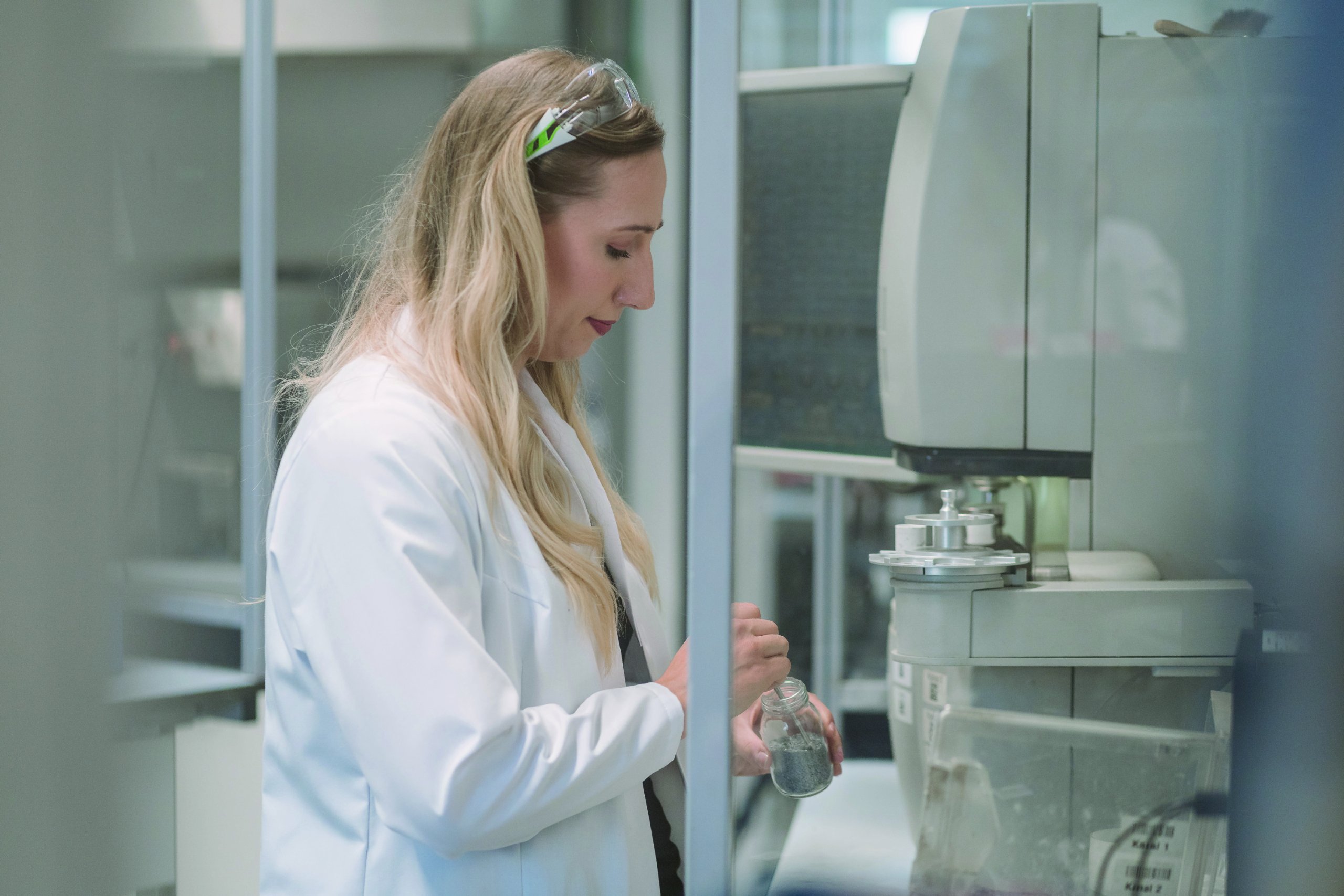 voestalpine Mitarbeiterin ist dabei, im Labor den Inhalt eines Glasbehälters in das Mikroskop zu legen