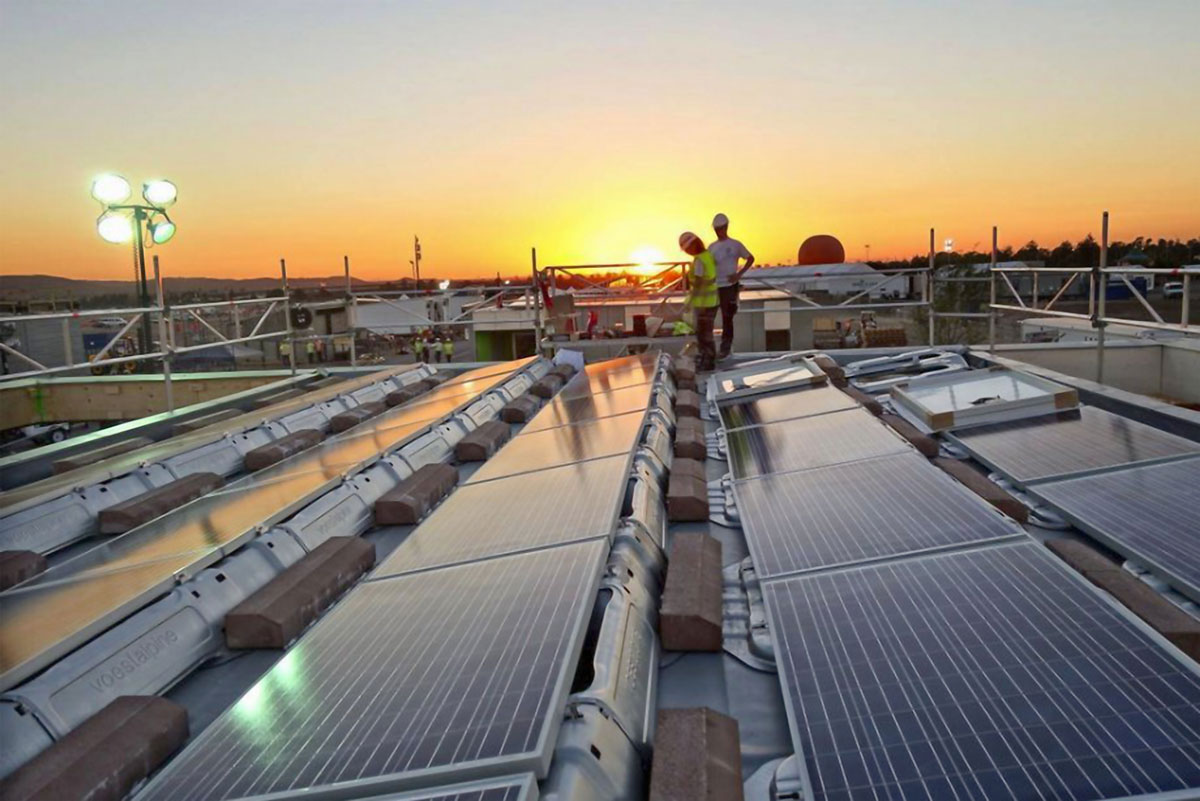 Solar power plant with two workers standing in front of a sunset
