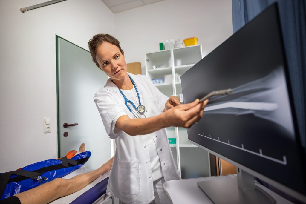 voestalpine Arbeitsmedizinerin Pippa P. zeigt einem Patienten ein Röntgenbild des Beinbruchs.