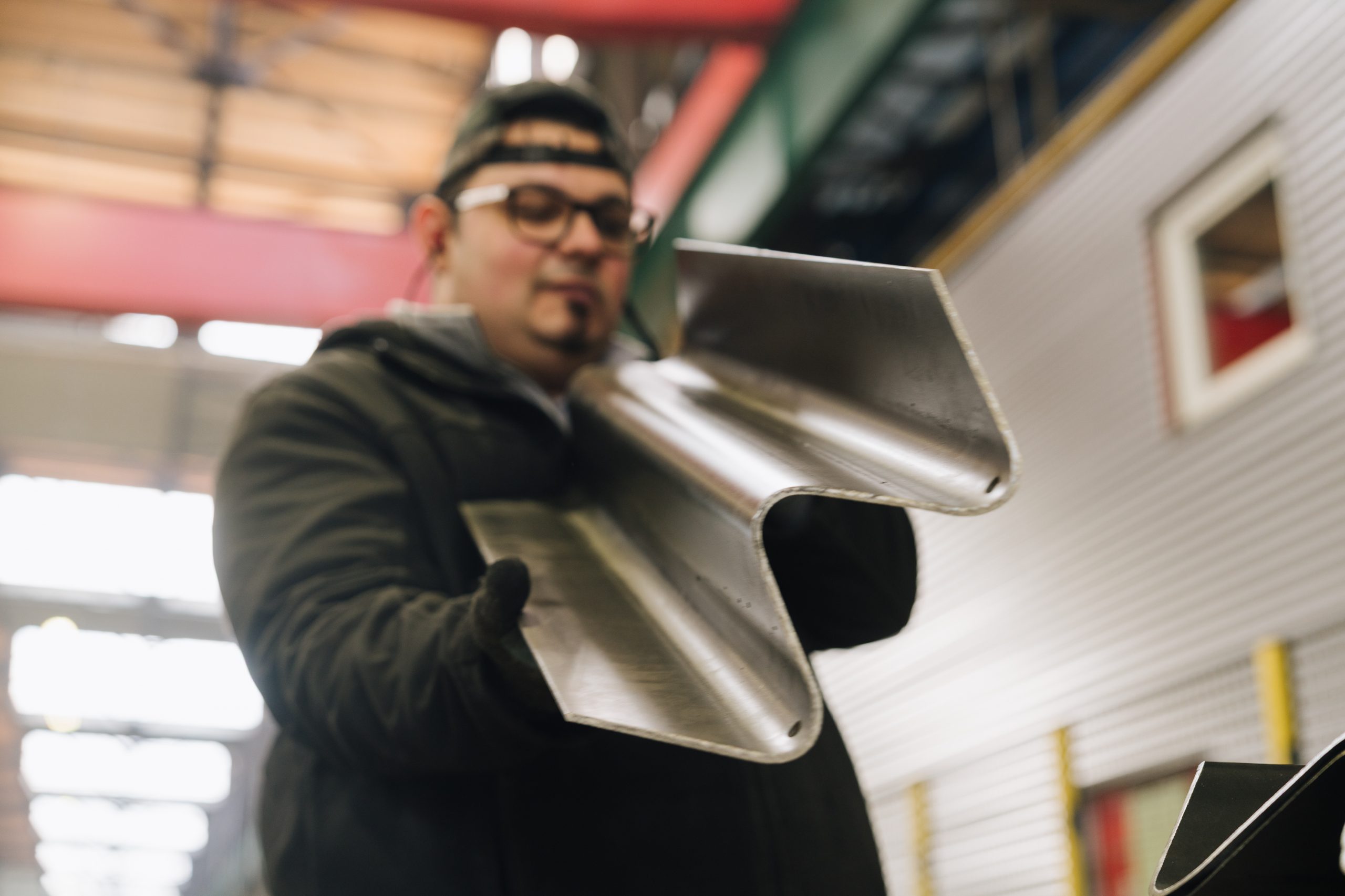 Mathias in industrial workwear holds a formed steel profile for road safety products in a modern metal processing production facility.