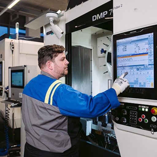Manuel stands in front of the milling machine and operates it with a large integrated display.