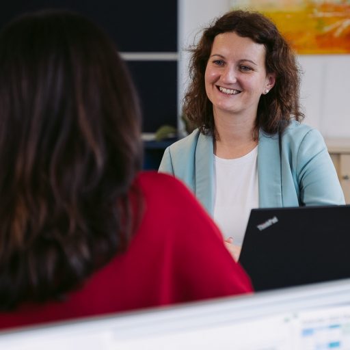 Michaela in conversation with a colleague in a modern office, symbolizing open communication and teamwork at voestalpine.