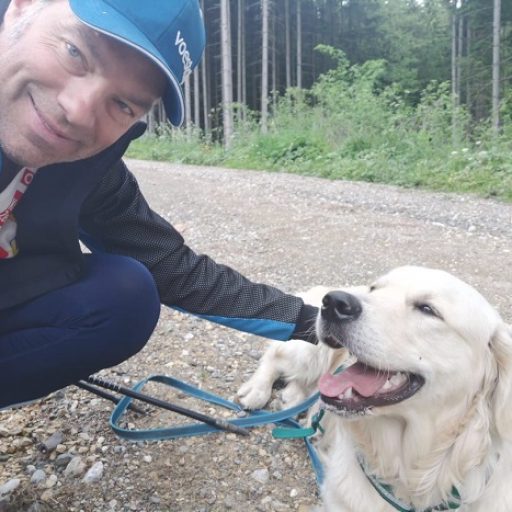 Johannes auf einem Forstweg mit seinem Hund, den er am Boden liegend streichelt