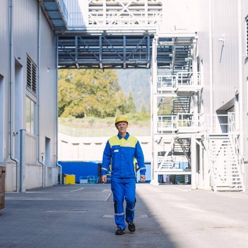 voestalpine employee Christoph walks in his protective work clothing between two factory halls towards the camera