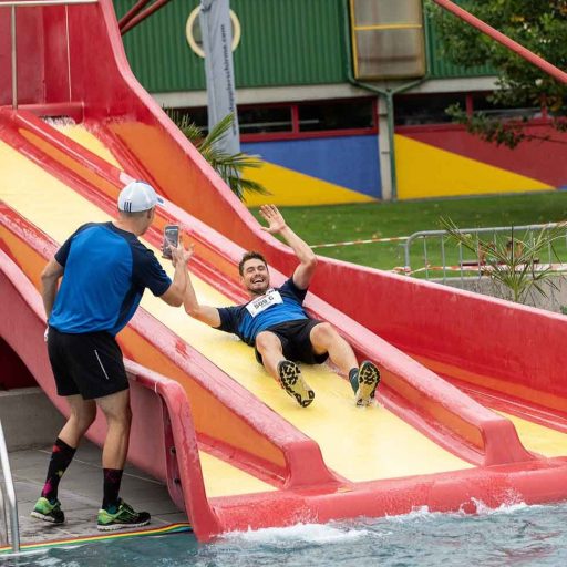 Teilnehmer rutscht am werk VI Lauf die Wasserrutsche ins das Becken