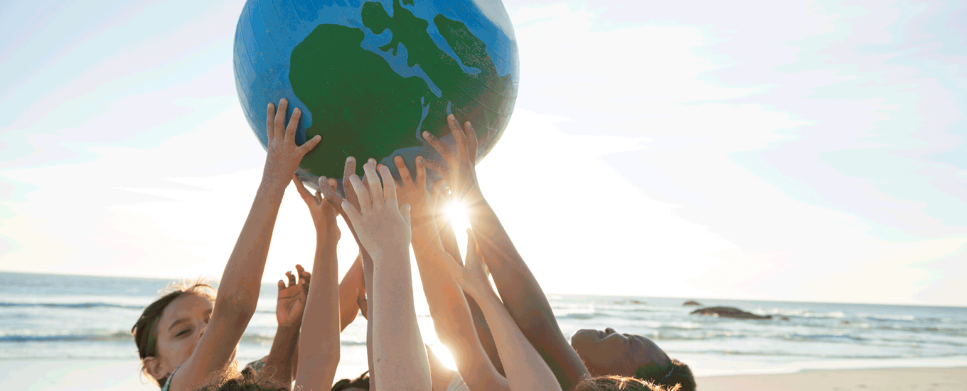 kids holding up a globe at a beach