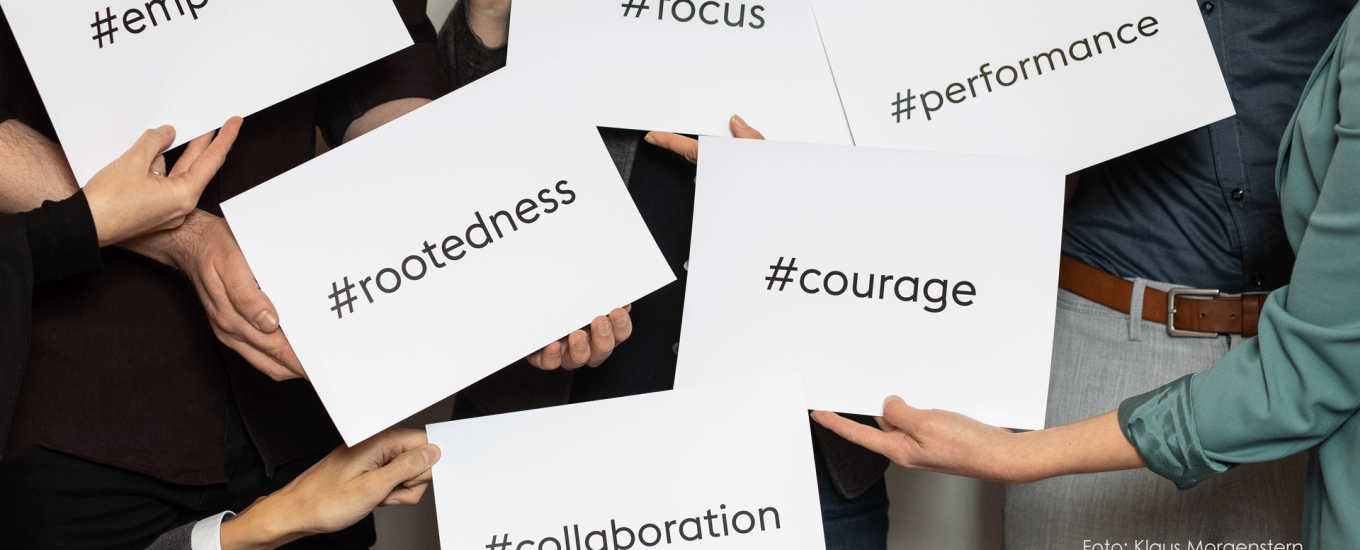 people holding up pieces of paper with the words "empathy", "focus", "rootedness", "collaboration", "corage" and "performance" written on them