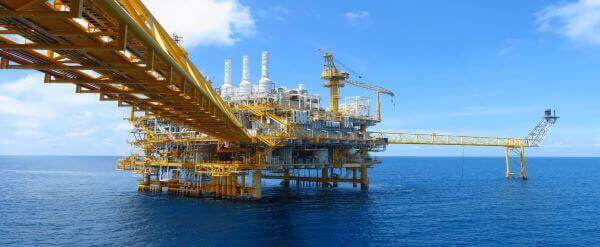 An oil and gas platform out at sea on a sunny day.