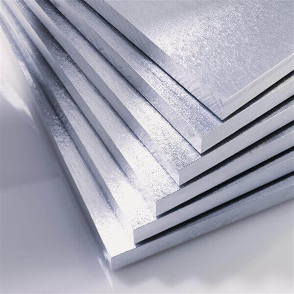 Stack of shiny, silver-colored metal sheets arranged in a slightly fanned-out manner, reflecting light on a smooth surface.