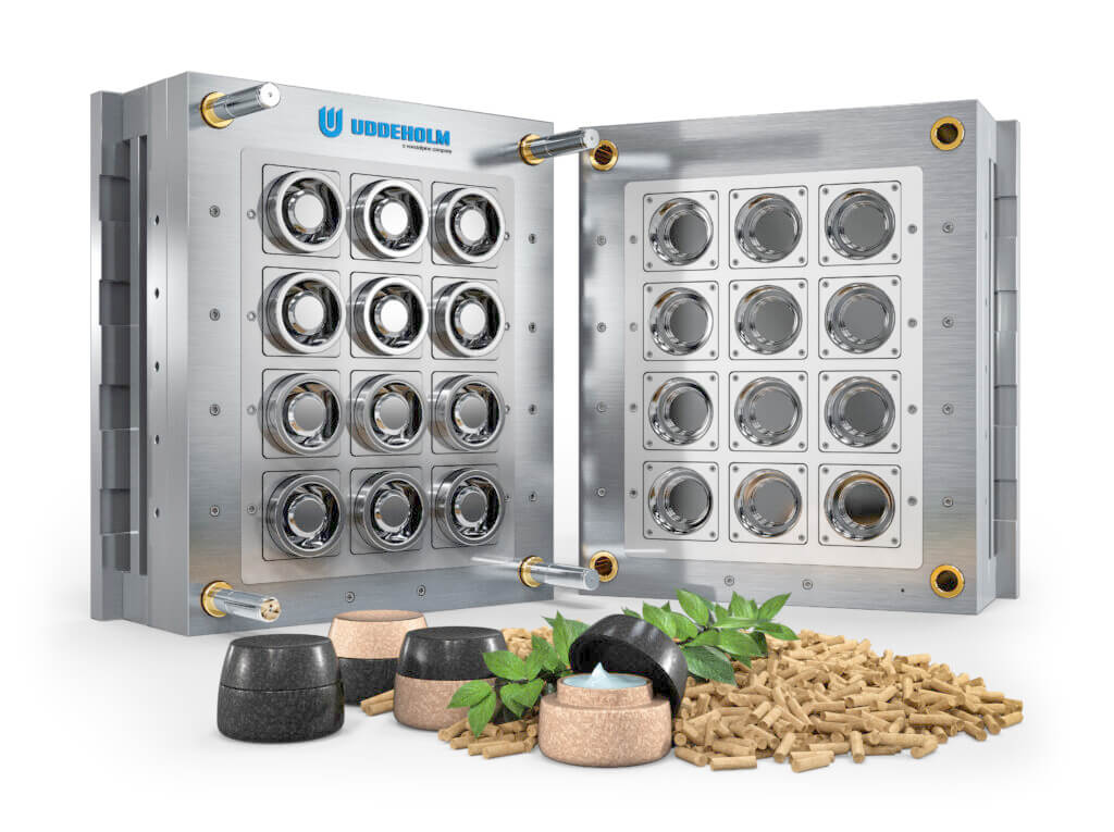 Open metal mold with circular cavities, crafted from premium plastic moulding tool steel, Uddeholm logo on top. In front are small black and brown containers, light brown pellets, and green leaves, all on a white background.