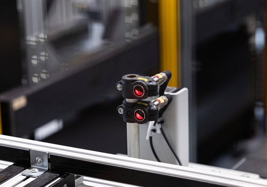 Close-up of two red optical sensors on an automated testing system.