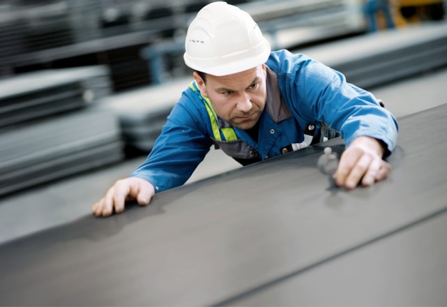A factory worker uses a device to test the flatness of a durostat steel plate