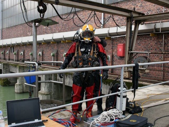 Feuerwehrtaucher in Spezialausrüstung bei einem Einsatz an einem Industriebecken.