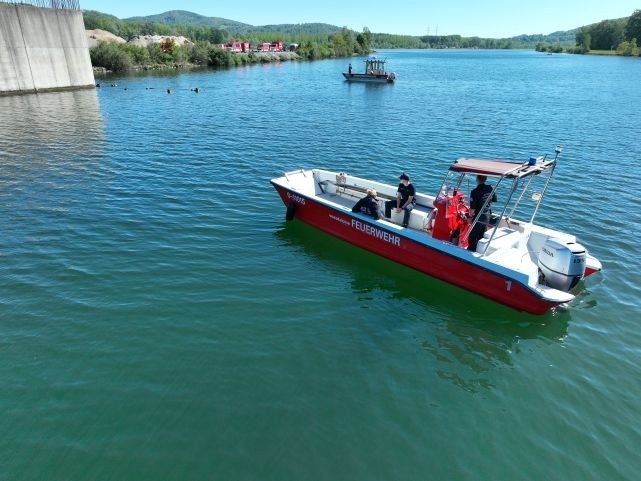Feuerwehrboot im Einsatz auf einem Gewässer bei einer Such- oder Rettungsaktion. Geben Sie Ihr Feedback zu BizChat ab.