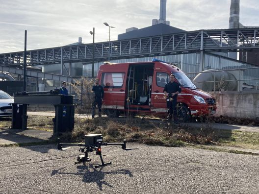 Einsatzdrohne und Feuerwehrfahrzeug auf einem Industriegelände im Bereitschaftseinsatz.