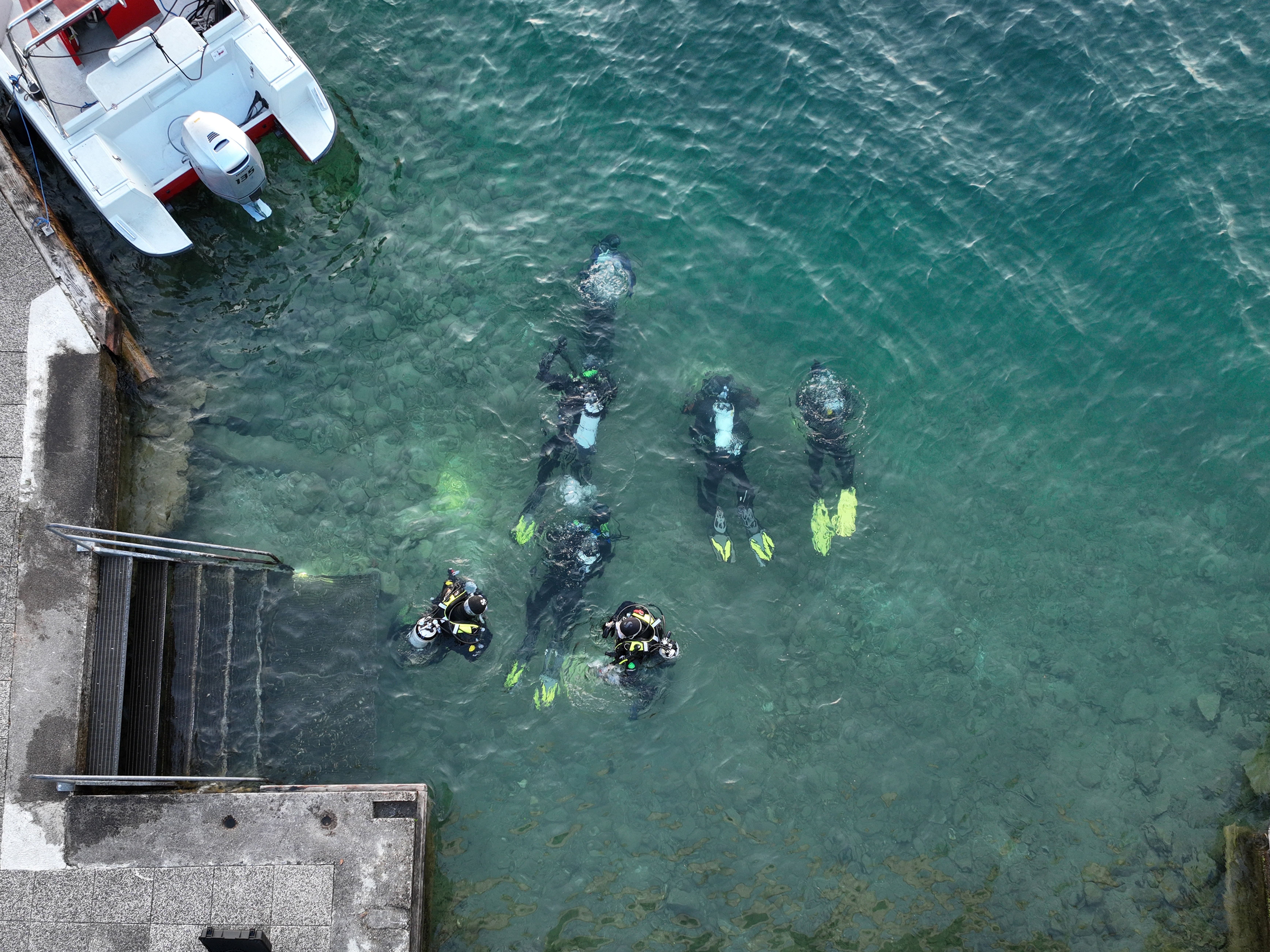 Feuerwehrtaucher bei einer Übung im Wasser nahe einer Anlegestelle.