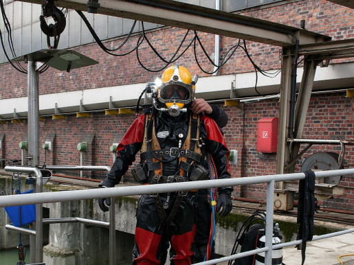 Feuerwehrtaucher in Spezialausrüstung vor dem Einstieg in ein Gewässer.