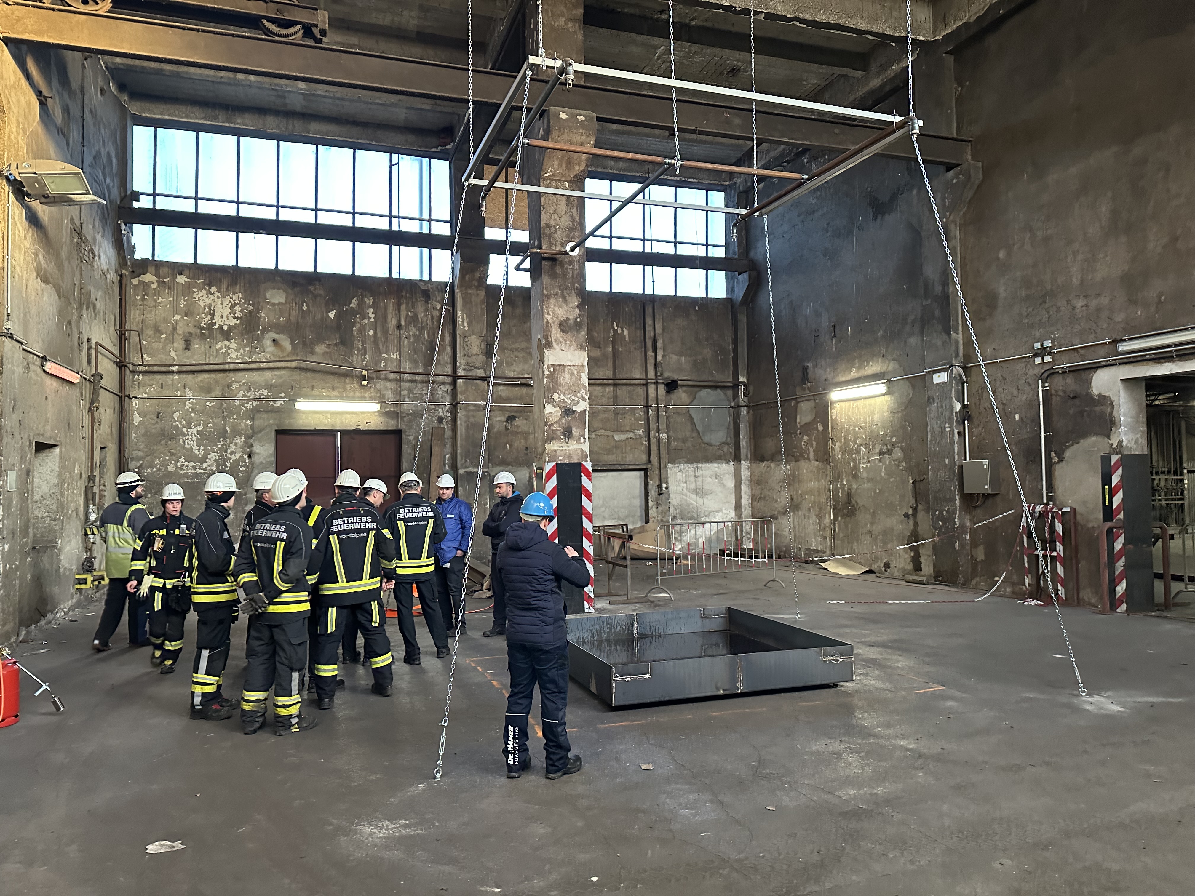 Feuerwehrkräfte bei einer Begehung und Brandschutzbewertung in einer Industriehalle.