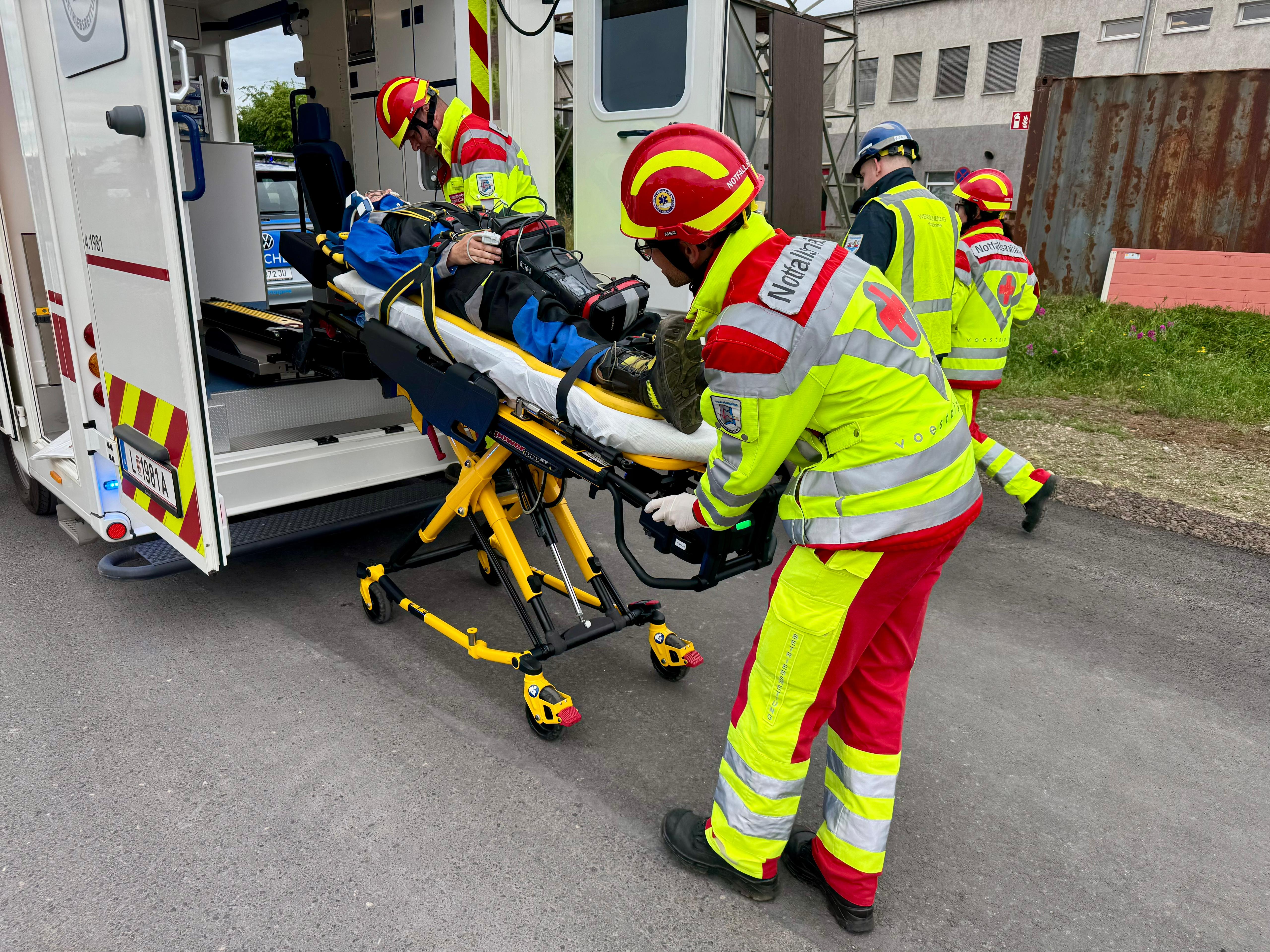 Notfallsanitäter beim Transport einer verletzten Person in ein Rettungsfahrzeug.