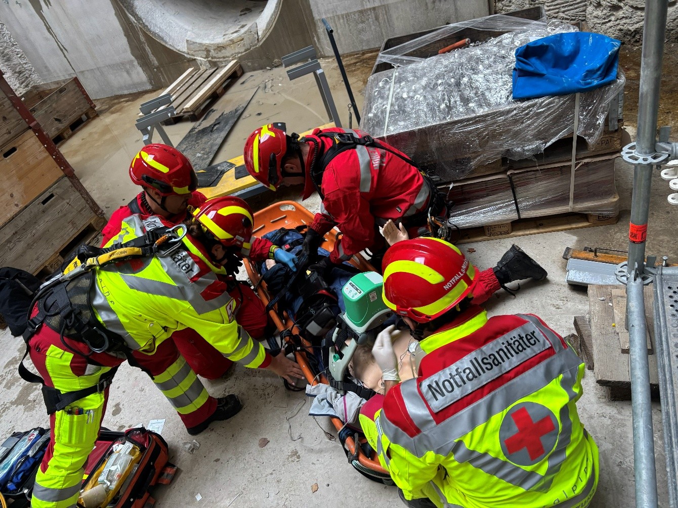 Notfallsanitäter bei der medizinischen Versorgung einer verletzten Person auf einem Betriebsgelände.