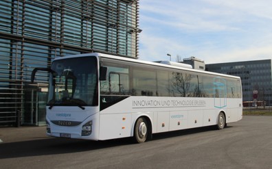 Der weiße Werkstour Bus steht auf dem Parkplatz vor dem Eingang der Stahlwelt. 